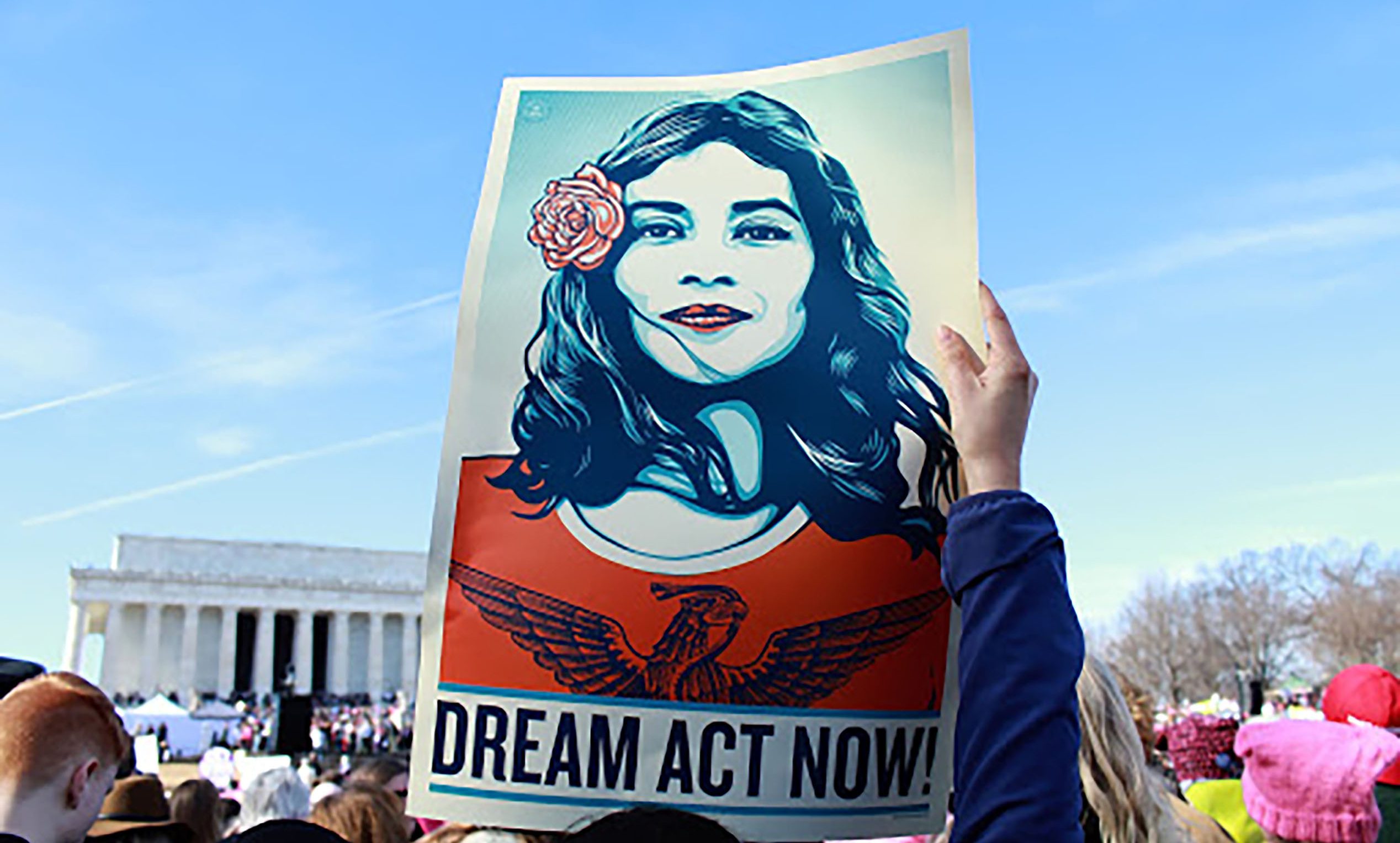 Woman holding a poster with text: Dream Act Now!