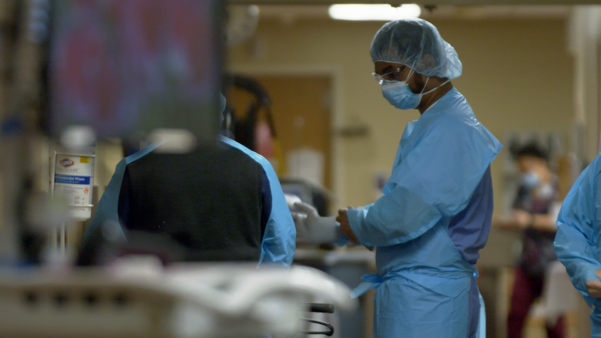 healthcare worker in scrubs and mask inside hospital hallway